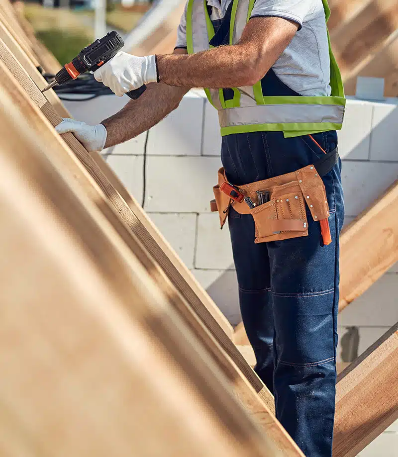 Artisan couvreur zingueur en plein travail sur une charpente, garantissant une installation précise et durable