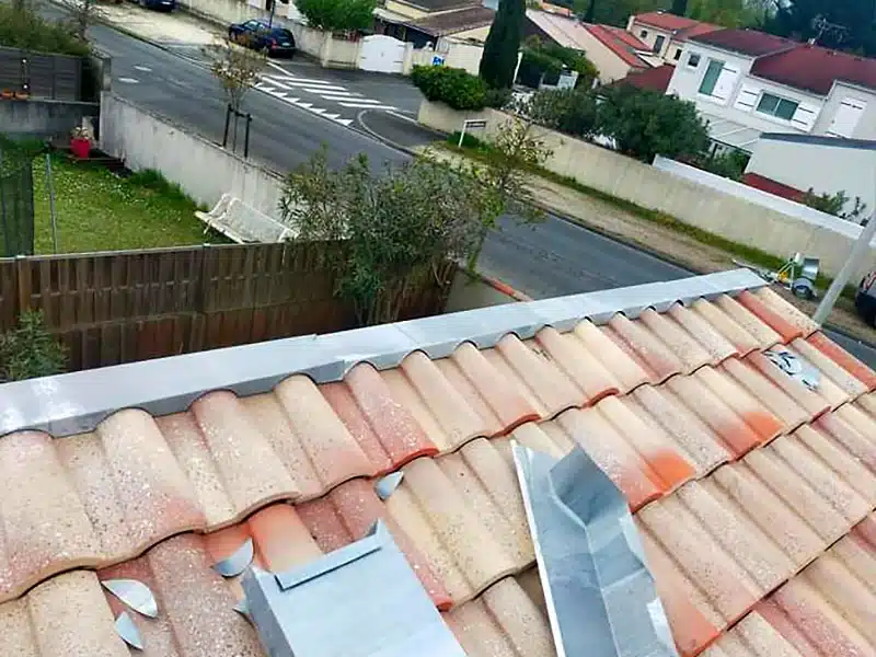 Travaux de zinguerie sur une toiture en tuiles, avec pose de chéneaux pour une évacuation efficace des eaux de pluie